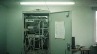 A dusty Canadian marketing agency server rack with the door half open exposed cables and a single fluorescent tube and a printed asset list taped to the door