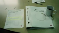 A binder labelled procurement best practices on a Canadian conference table beside a printed vendor scorecard with rows highlighted in yellow
