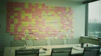 A wall of pink and yellow post-it notes on a Canadian marketing agency boardroom wall labelled with hand-written MSP warning signs in blue marker